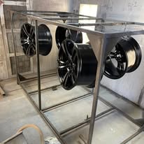 Glossy black powder coated car wheels on a rack