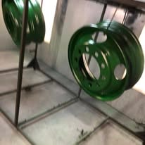 Green powder coated steel wheels hanging in the paint booth
