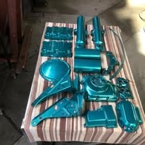 Turquoise powder coated motorcycle engine parts laid on a table